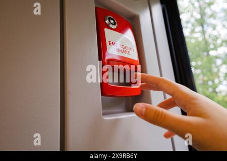 In der Abbildung aktiviert eine Person eine rote Taste, die an einer Wand angebracht ist. Die Szene zeigt eine Geste, bei der ein Finger den Knopf drückt, mit Elementen Stockfoto