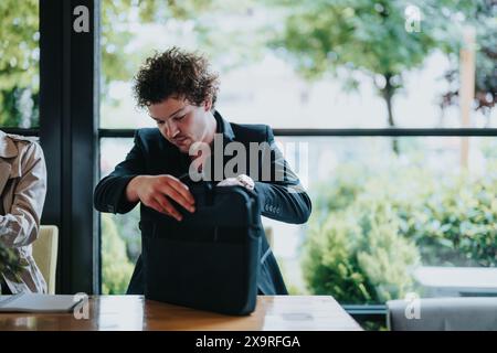 Geschäftsmann, der Dokumente in einer Aktentasche in einem modernen, hellen Café organisiert Stockfoto