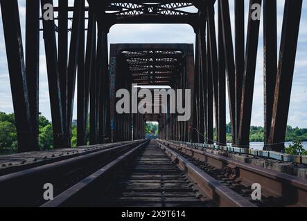 Eine leere, symmetrische Eisenbahnbrücke, die in einen üppig grünen Wald am Rande von Ottawa Ontario führt Stockfoto