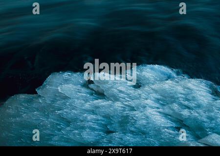 Nahaufnahme von Eiszapfen, die sich an der Seite eines sich schnell bewegenden Baches bilden. Stockfoto