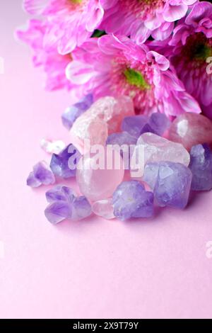 Wunderschöne Amethyst-violette Kristalle mit rosa Chrysanthemen-Blüten. Magische Amulette. Stockfoto