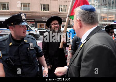 Ein Mitglied von Neturei Karta, Zentrum, die ultra-orthodoxe, antizionistische Juden sind, protestiert auf der Straße in der Nähe eines israelischen Unterstützers, rechts, während der 59. Jährlichen Israel Day Parade. Die Israel Day Parade zum Gedenken an die jüdische Kultur zieht Nachtschwärmer, Wagen und israelisch-amerikanische Organisationen nach Midtown Manhattan, New York City. Die Parade fand fast acht Monate nach Beginn des israelisch-Hamas-Krieges statt. Die diesjährige Parade konzentrierte sich auf die israelische Solidarität im andauernden Krieg. Das New York City Police Department erhöhte die Sicherheit für die Parade aufgrund von Befürchtungen der propalästinensischen Proteste. Stockfoto