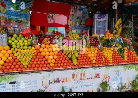 Jemaa el-Fnaa, Marrakesch, Marokko - 18. März 2024: Ein lebhafter Obststand mit verschiedenen frischen Früchten unter einem mit Moroc verzierten Baldachin Stockfoto