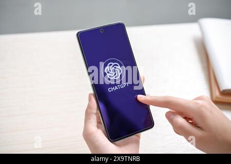 Chiang mai, Thailand - 03. Juni 2024: Ein Nahaufnahme einer Hand einer Frau, die ein Smartphone mit dem ChatGPT-Logo auf dem Bildschirm an einem Tisch im Haus hält. ch Stockfoto