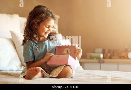 Spielzeug für Mädchen, Musikbox und Ballerina zu Hause mit einem Lächeln auf dem Bett für Lieder, Melodie und Sound im Mockup-Raum. Kind, verspielt und glücklich im Schlafzimmer Stockfoto