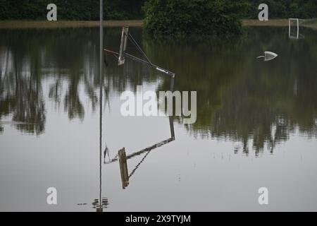 Meckenbeuren Brochenzell, Deutschland. Juni 2024. Ein Basketballkorb spiegelt sich auf dem überfluteten Sportplatz wieder. Die Schussen hatten Teile von Meckenbeuren überflutet. Quelle: Felix Kästle/dpa/Alamy Live News Stockfoto