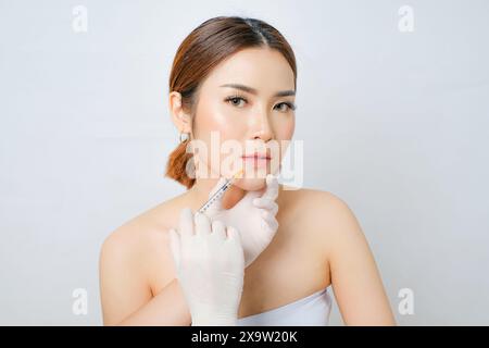 Erreichen des Gesichtsausgleichs Lippen- und Kinnfüllungen für asiatische Frauen isolierter weißer Hintergrund. Ideal für Hautpflegeanzeigen, Schönheitskliniken, Salon und Spa Stockfoto
