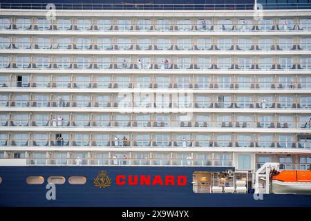 Passagiere schauen aus ihren Kabinen, während Cunards Queen Anne mit Feuerschleppern in die Mersey segelt, bevor sie eine Namenszeremonie am Liverpool Pier Head im Rahmen einer einführenden „Runde der Ehre“-Reise um die britischen Inseln antreten. Bilddatum: Montag, 3. Juni 2024. Stockfoto