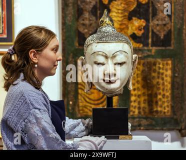 Olympia Auctions, London, Großbritannien. Juni 2024. Ein geschnitzter und bemalter Marmorkopf von Buddha, Burma, um 1900mit langen Ohrläppchen, rot bemalten Lippen und schwarz bemalten gewölbten Augenbrauen, eng gelockten schwarz bemalten Haaren und Usnisa mit knospenförmigem Finial, montiert, 43 cm hohe Provenienz: Privatsammlung, Kensington, London Est £1,000-1,500 Auktion 5. Juni 2024. Quelle: Paul Quezada-Neiman/Alamy Live News Stockfoto