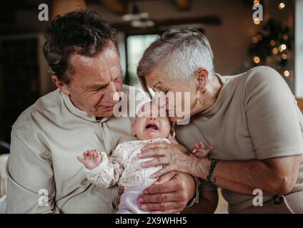 Großeltern halten ein weinendes Mädchen, beruhigen sie, beruhigen sie. Starke Bindung zwischen Großeltern und Enkel. Stockfoto