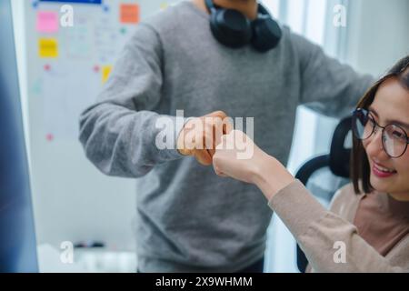 asiatische und indische Entwicklerteams klatschen Hand für Projekterfolg mit Software-Computer im Büro Stockfoto