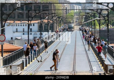PORTO, PORTUGAL - 24. APRIL 2024: Touristen überqueren die Eisenbahn vor der U-Bahn auf der Luis 1 Brücke in Porto, Portugal Stockfoto