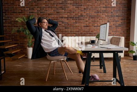 Lustiger Geschäftsmann im formellen Anzug und weiche Hausschuhe, der online arbeitet Stockfoto