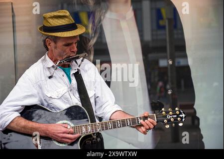 Straßenmusiker spielt Gitarre & Harmonica männlicher Straßenmusiker spielt Gitarre und eine Harmonica im Lijnbaan Shopping Center, um Besucher und Kunden zu unterhalten. Rotterdam, Niederlande. Rotterdam Lijnbaan Zuid-Holland Nederland Copyright: XGuidoxKoppesxPhotox Stockfoto