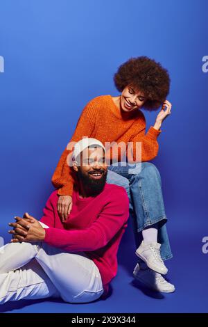 Afroamerikanische Freunde in lebendiger Kleidung sitzen zusammen und fördern eine tiefe Bindung in der beruhigenden blauen Umgebung. Stockfoto