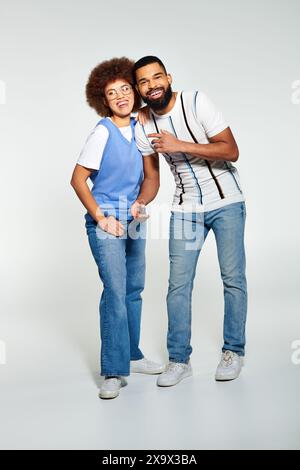 Ein afroamerikanischer Mann und eine afroamerikanische Frau in modischer Kleidung, die zusammen vor grauem Hintergrund posieren. Stockfoto