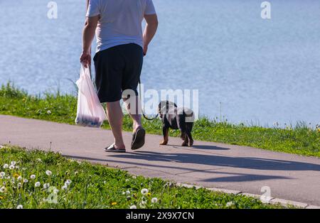 Ein Mann und ein Hund an der Leine neben einem Gewässer. Stockfoto