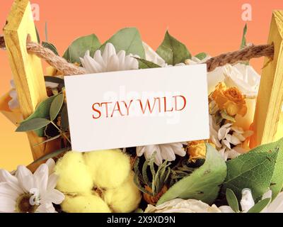 Finanzkonzept bedeutet „Stay Wild“ mit Inschrift in einem Blumenstrauß auf einer weißen Visitenkarte Stockfoto