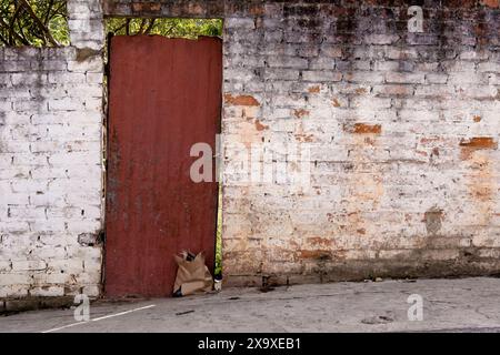 Die weiße Ziegelfassade mit einem Papiertüten an der wackeligen Metalltür eines ursprünglichen Hauses in der Stadt Arcabuco in den östlichen Anden Stockfoto