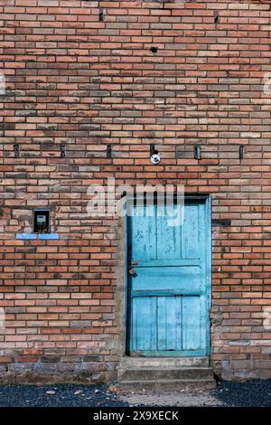 Die alte blaue Holztür in einer Backsteinmauer eines Gebäudes in der Stadt Arcabuco, in den östlichen Andenbergen Zentral-Kolumbiens. Stockfoto