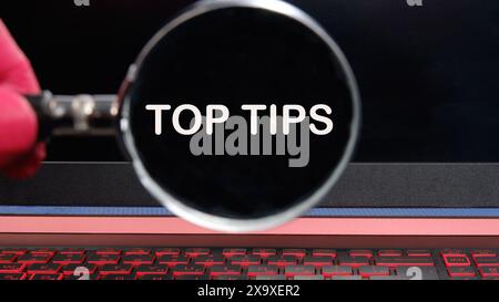 Business- und Top-Tipps-Konzept, Kopierbereich. Symbol für Top-Tipps. Konzeptworte Top Tips Text erschien durch eine Lupe auf einem dimmeren Laptop-Bildschirm Stockfoto