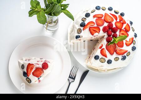 Meringue-Kuchen oder Pavlov's Dessert mit Schlagsahne, Erdbeeren, Heidelbeeren und Himbeeren auf einem weißen Tisch. Hochwertige Fotos Stockfoto