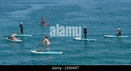 Ein Panoramablick von Urlaubern, die Stand Up Paddleboards in Newquay Bay in Cornwall nutzen. Stockfoto