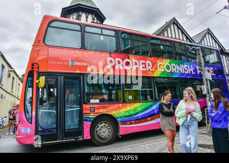 Ein Doppeldeckerbus, der dekoriert ist und an der lebhaften farbenfrohen Cornwall Prides Pride Parade im Zentrum von Newquay in Großbritannien teilnimmt. Stockfoto