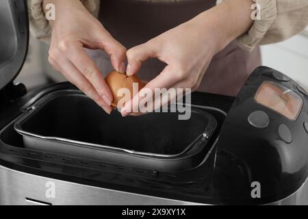 Teig herstellen. Frau, die Ei in die Brotbackpfanne bricht, Nahaufnahme Stockfoto