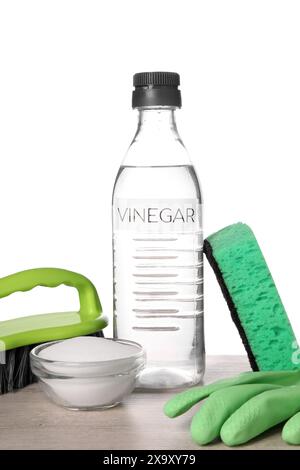 Natürliche Reinigungsmittel. Essig in der Flasche, Natron, Handschuh, Schwamm und Bürste auf hellem Holztisch vor weißem Hintergrund Stockfoto