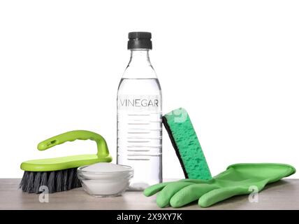 Natürliche Reinigungsmittel. Essig in der Flasche, Natron, Handschuh, Schwamm und Bürste auf hellem Holztisch vor weißem Hintergrund Stockfoto
