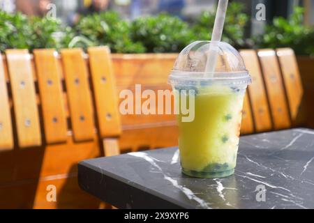 Erfrischender gelber Bubble-Tee mit Tapiokaparlen steht auf einem Marmortisch vor einem Café, Stockfoto