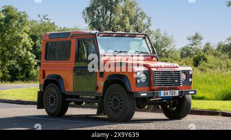 Stony Stratford, Großbritannien - 2. Juni 2024: 2003 orange Land Rover Defender 90 G4 le Oldtimer auf einer britischen Landstraße Stockfoto