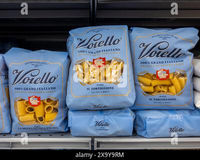 Italien - 08. Mai 2024: Voiello-Pasta in blauen Verpackungen im Regal zum Verkauf im italienischen Supermarkt. Mezze Maniche und Tortiglioni Makkaroni Stockfoto