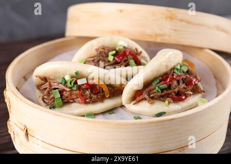 Leckere Gua bao (Schweinebauchbrötchen) in Bambusdampfer auf dem Tisch, Nahaufnahme Stockfoto