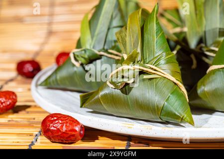 Zongzi ist ein traditionelles chinesisches Reisgericht aus klebrigem Reis, gefüllt mit verschiedenen Füllungen und in Bambusblättern gewickelt. Stockfoto