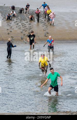 Führende Läufer beim Maldon Mud Race 2024 in Maldon, Essex, Großbritannien, im Schlamm und Wasser des Flusses Chelmer. Traditionelle Wohltätigkeitsveranstaltung. Stockfoto