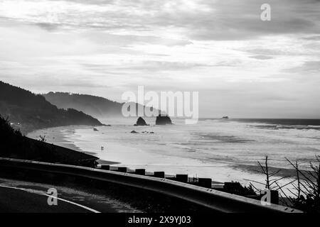 Geschwungene Straße am Meer mit hoch aufragenden Felsen im Hintergrund Stockfoto