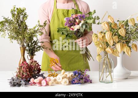 Getrocknete Blüten. Blumenläuferin, die getrocknete Blumen zu einem schönen Blumenstrauß anordnet. Nachhaltige Floristik. Einrichtung eines Wohnhauses mit getrockneten Blumen. Stockfoto