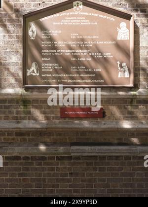 Hinweisschild vor der katholischen christlichen Karmeliterkirche unserer Lieben Frau von Mount Carmel und St. Simon Stock, Kensington, London, England. Stockfoto