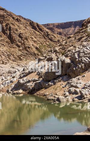 Der Fish River in der kargen Wüstenregion, umgeben von hellen Felsen, reflektiert die steilen Klippen der Canyons Stockfoto