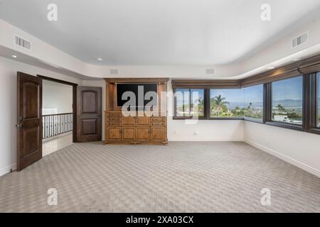 Ein Schlafzimmer mit geräumigen Fenstern und einem wandmontierten Fernseher in Encino, Kalifornien Stockfoto