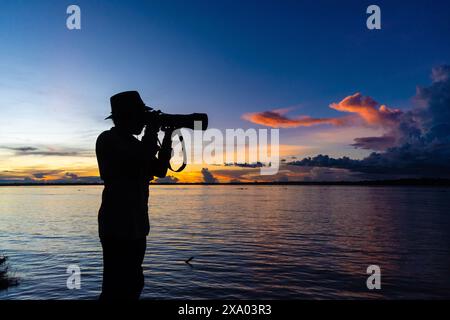 Silhouette eines Fotografen mit Hut und Flusslandschaft Stockfoto