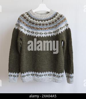 Foto eines aus isländischer Wolle gestrickten Lopeysa-Pullovers, brauner grüner Pullover mit großer bunter Passe in traditionellem nordischem Strickmuster Stockfoto