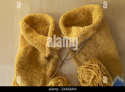 Flache Lay-Fotografie eines isländischen Wollstrickpullover-Ärmeln im Gange, Magic Loop-Technik mit gelben Garnbällchen und kreisförmigem Bedarf Stockfoto