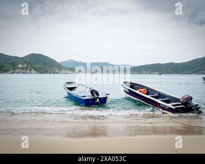 Zwei kleine Boote am Strand mit Bergen im Hintergrund Stockfoto