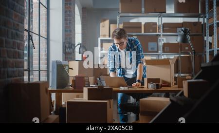 Inventory Manager verpackt einen stilvollen Fahrradsitz, der online an einen Kunden verkauft wird. Ein kleines Papppaket für das Porto vorbereiten. Junger Inhaber kleiner Unternehmen, der im Lager arbeitet. Stockfoto