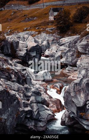 Fluss fließt durch felsiges Tal in der Nähe von House in Field Stockfoto