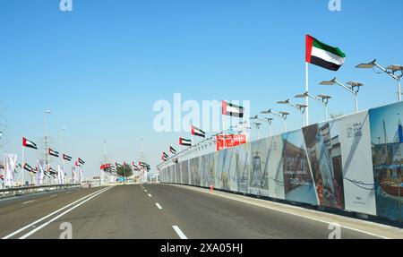 Abu Dhabi, VAE, 11. januar. 2024.- Blick auf eine Dubai Autobahn mit vielen Autos und Flaggen an der Seite. Hghway und Nationalflaggen der vereinigten staaten Stockfoto