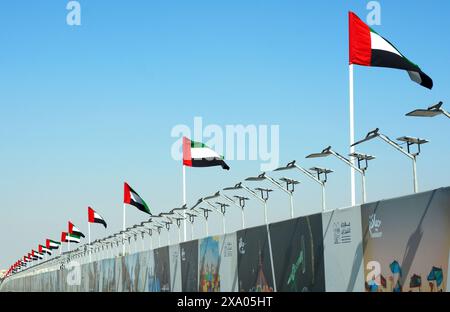 Abu Dhabi, VAE, 11. januar. 2024.- Blick auf eine Dubai Autobahn mit vielen Autos und Flaggen an der Seite. Hghway und Nationalflaggen der vereinigten staaten Stockfoto